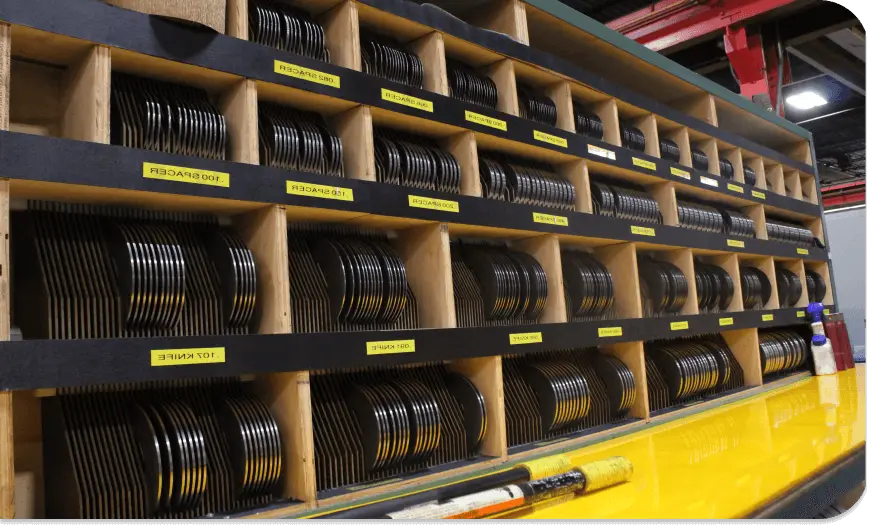 Coils of narrow spring and strip steel stored in labeled racks at Admiral Steel