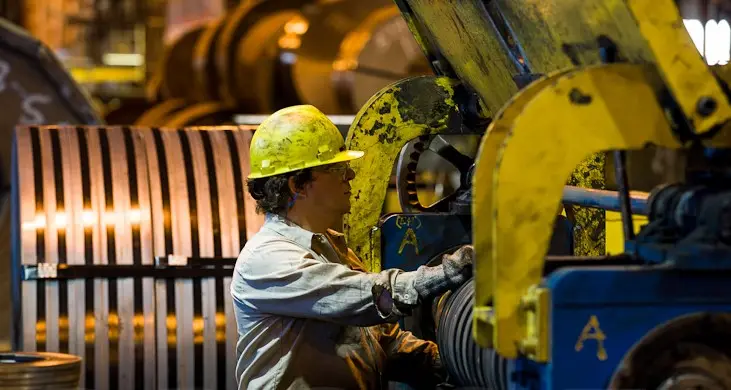 Operator setting up a slitting line beside freshly slit steel coils