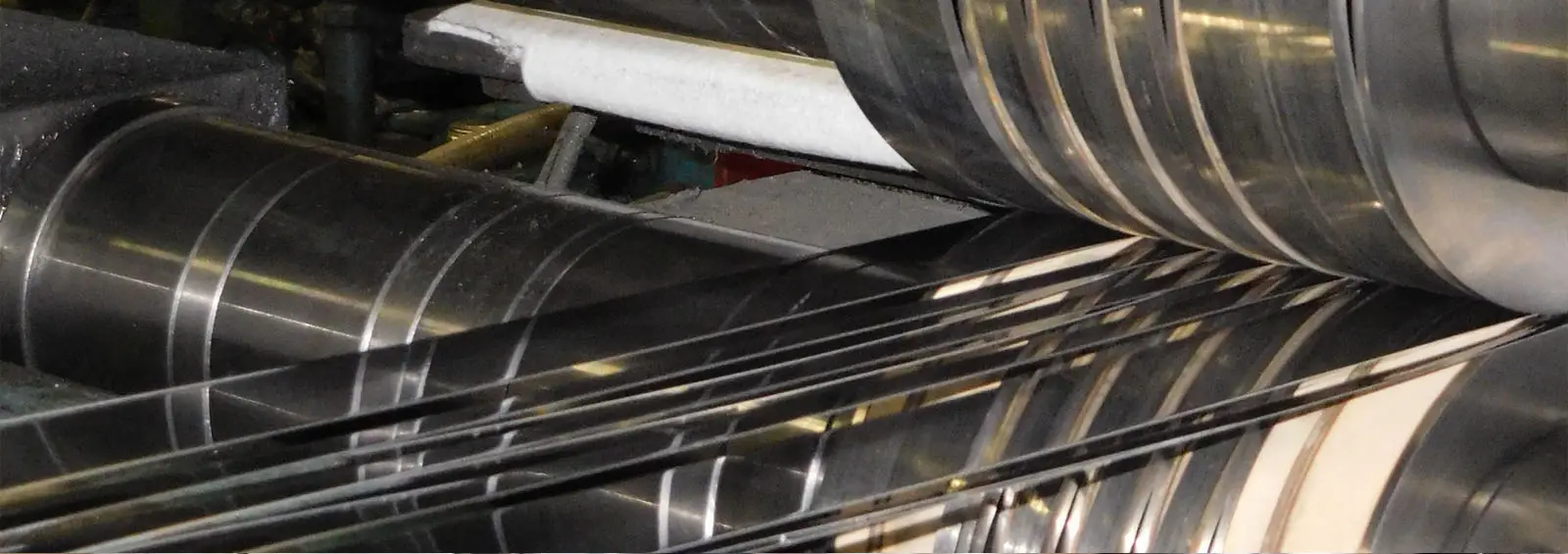 Close-up of slit metal strip passing between the knives of an Almetals slitter