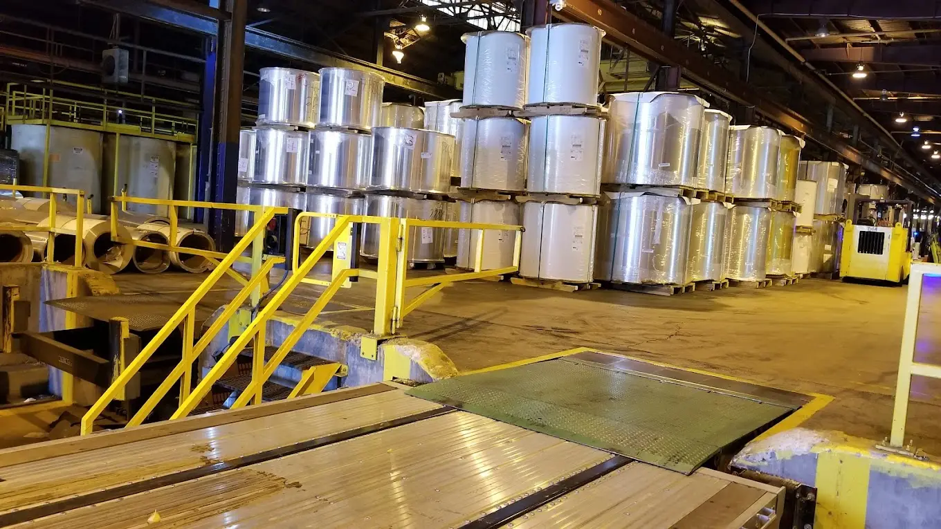 Stacked aluminum coils staged on the floor of the AZZ Precoat Metals St. Louis coil coating plant