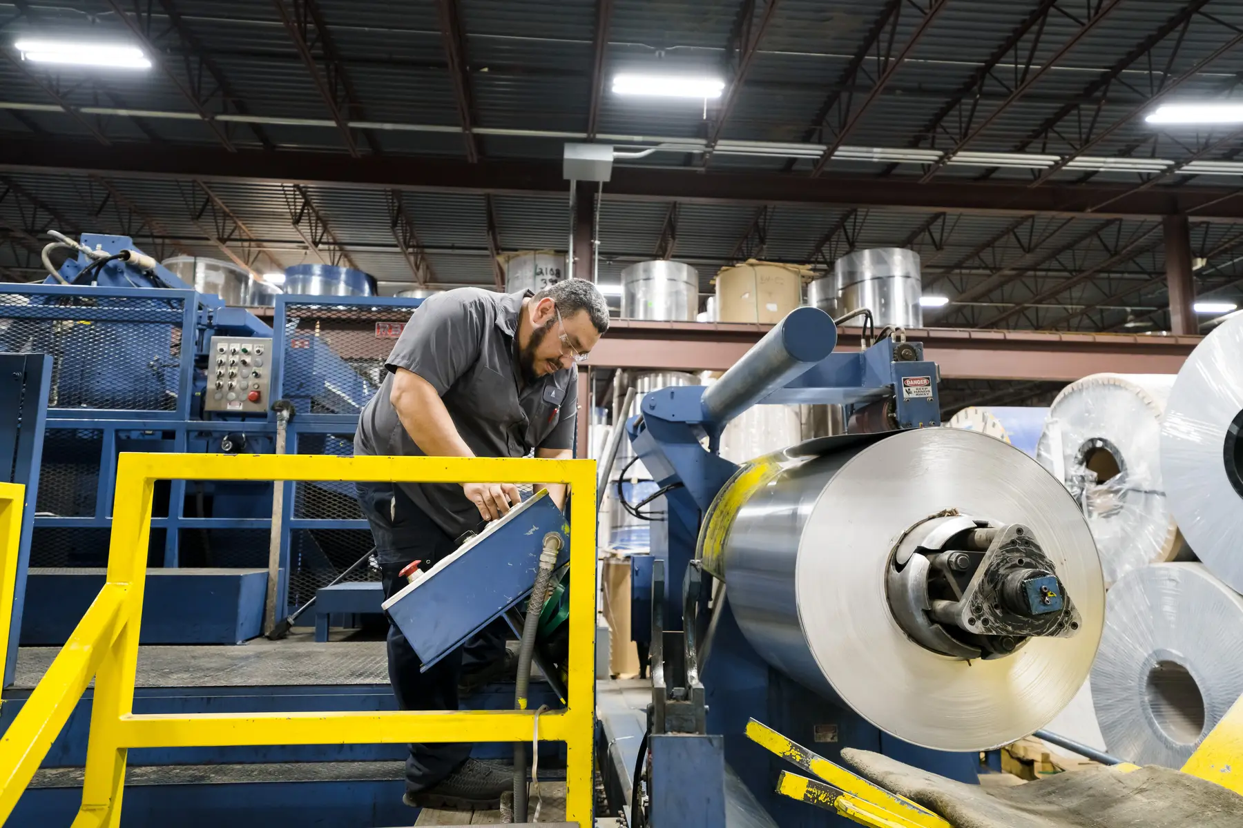Operator loading an aluminum coil onto a processing line uncoiler
