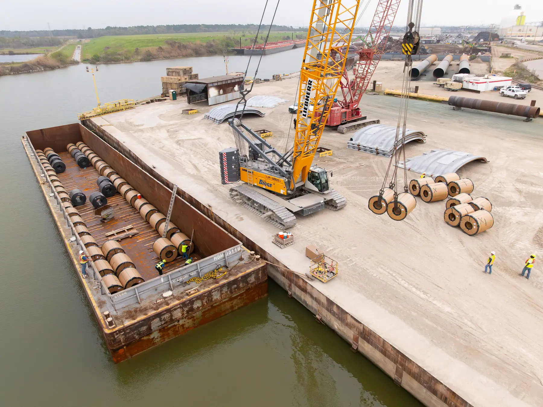 Crawler crane unloading steel coils from a barge at Bayou Processing & Storage's Houston dock