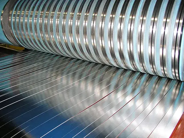 Narrow precision-slit steel strips running through a Braner slitter at Berlin Metals