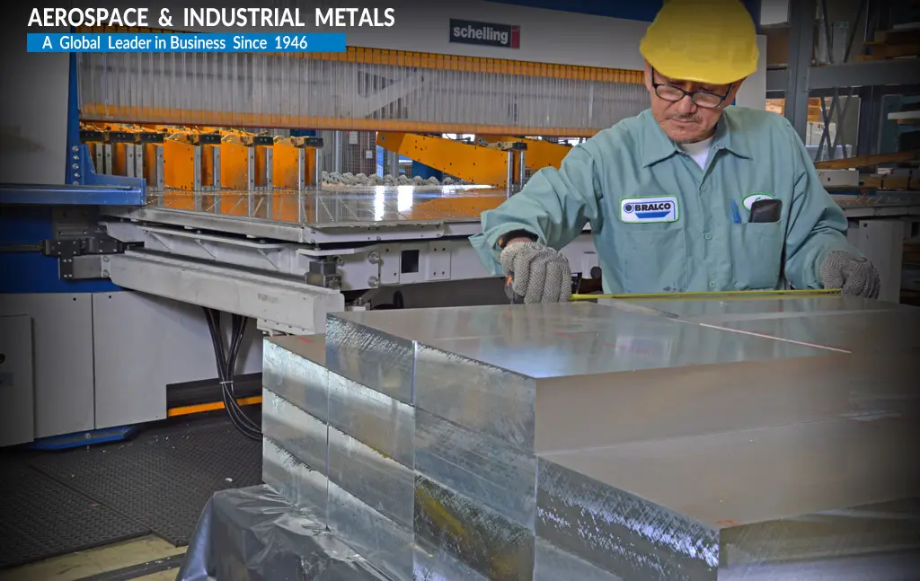 Saw-cut aluminum plate blocks being measured beside a Schelling saw at Bralco Metals