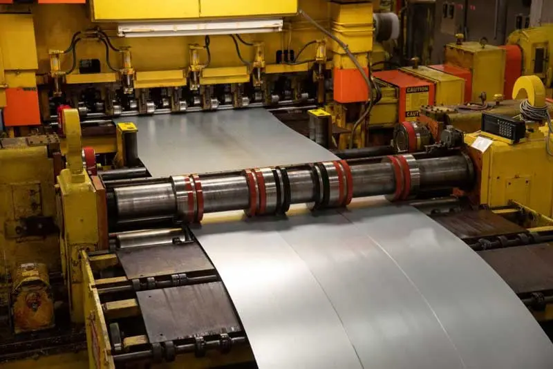 Steel strip passing through the slitter knives on Chesterfield Steel's slitting line