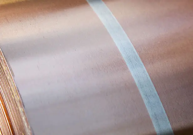Close-up of a copper coil with a continuous silver-colored inlay stripe