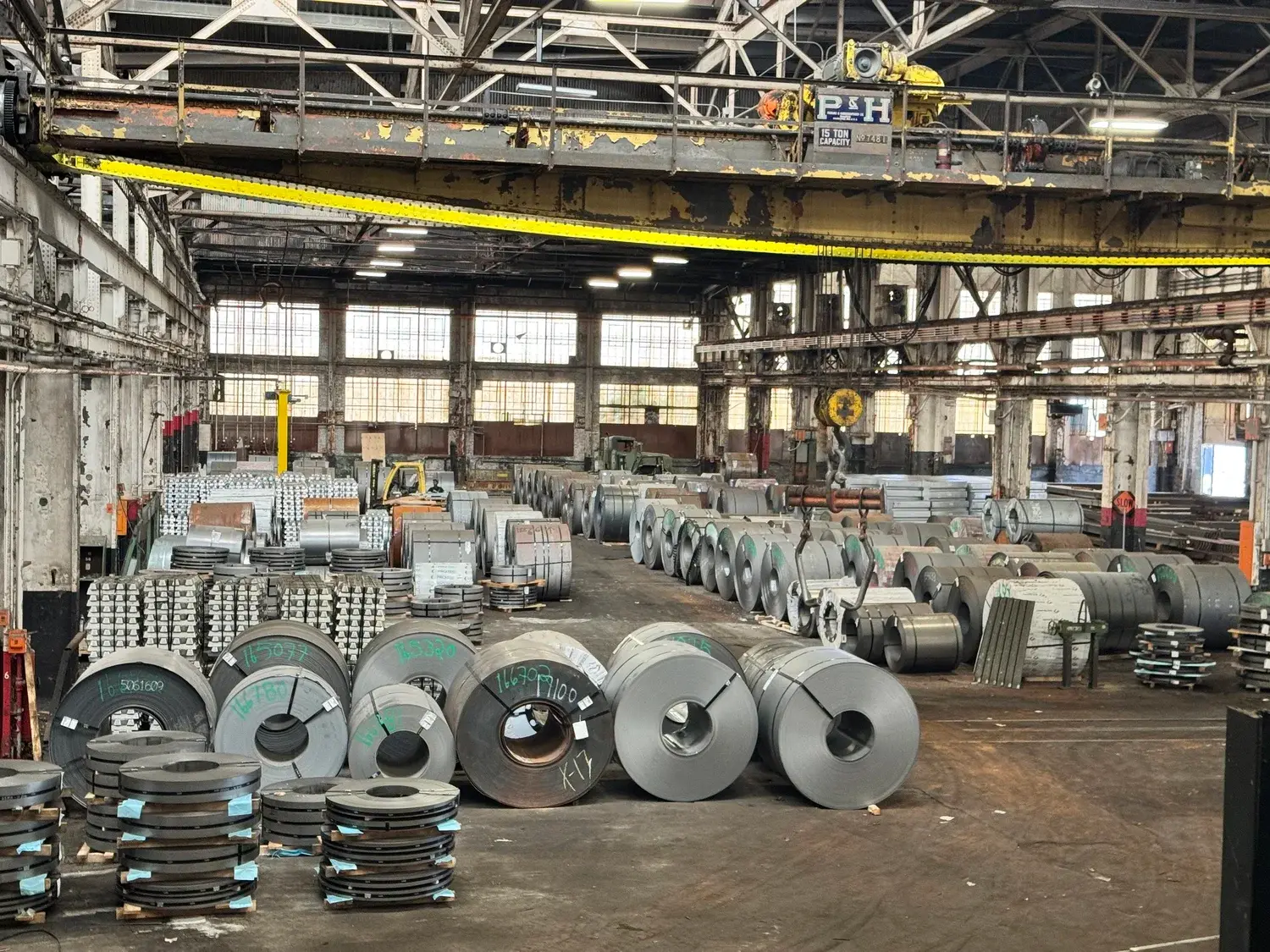 Rows of steel coils and slit coil stacks under overhead cranes in Collier Metals' Atlanta warehouse