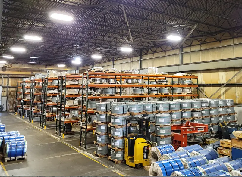 Racks and floor stacks of packaged slit coils inside a Colonial warehouse