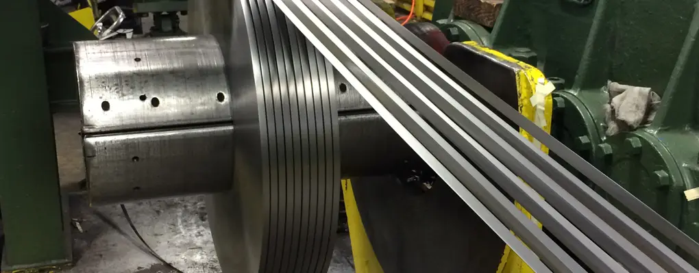 Narrow slit metal strands running through the slitter knives at Consolidated Metal Service