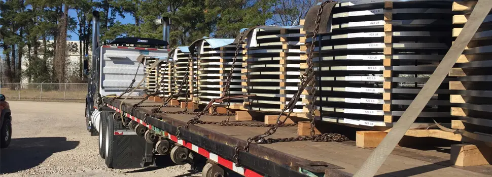 Slit steel coils on skids chained to a flatbed trailer for delivery