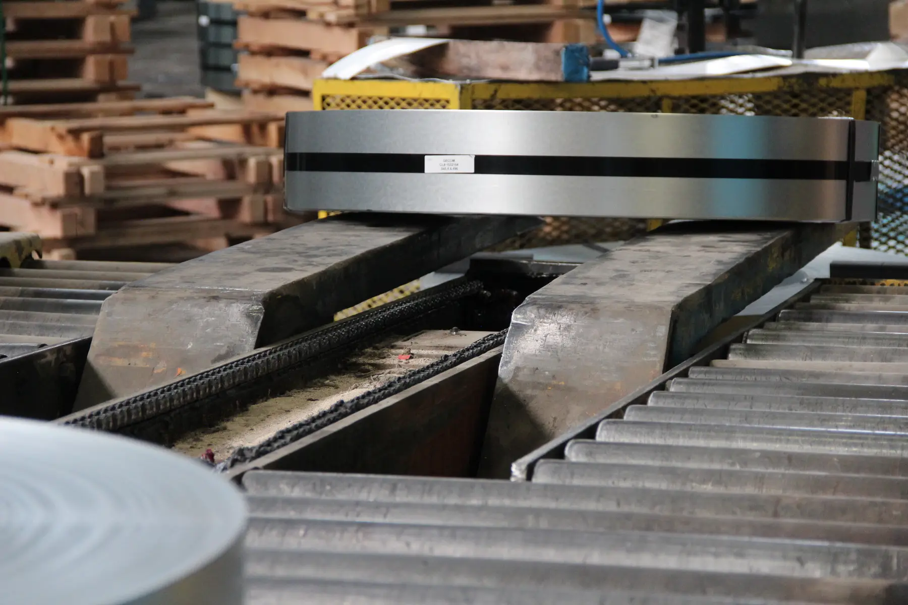 Slit steel coil staged above the roller conveyor on a Custom Steel Processing line