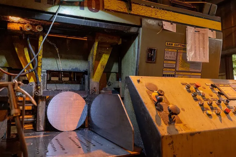 Horizontal band saw cutting large-diameter round steel bar at ECONSTEEL in Erie