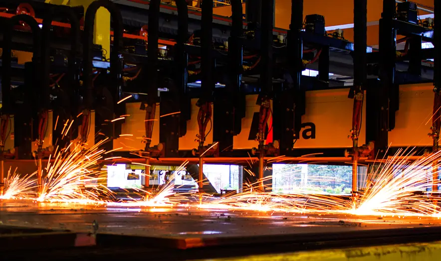 Multi-torch CNC flame cutting machine throwing sparks as it cuts steel plate at Farwest Steel