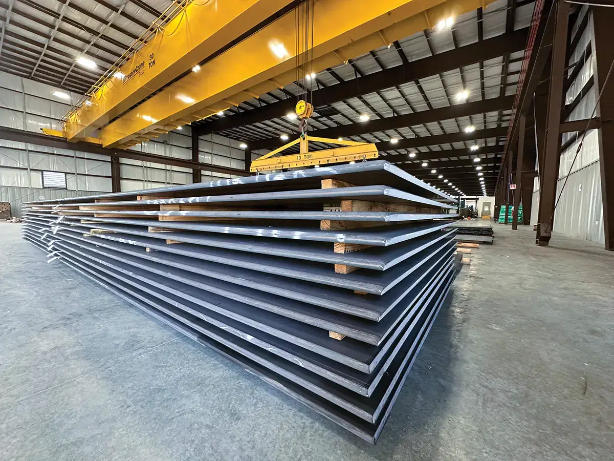 Overhead crane lifting stacked cut-to-length steel plate inside the Sinton, Texas facility