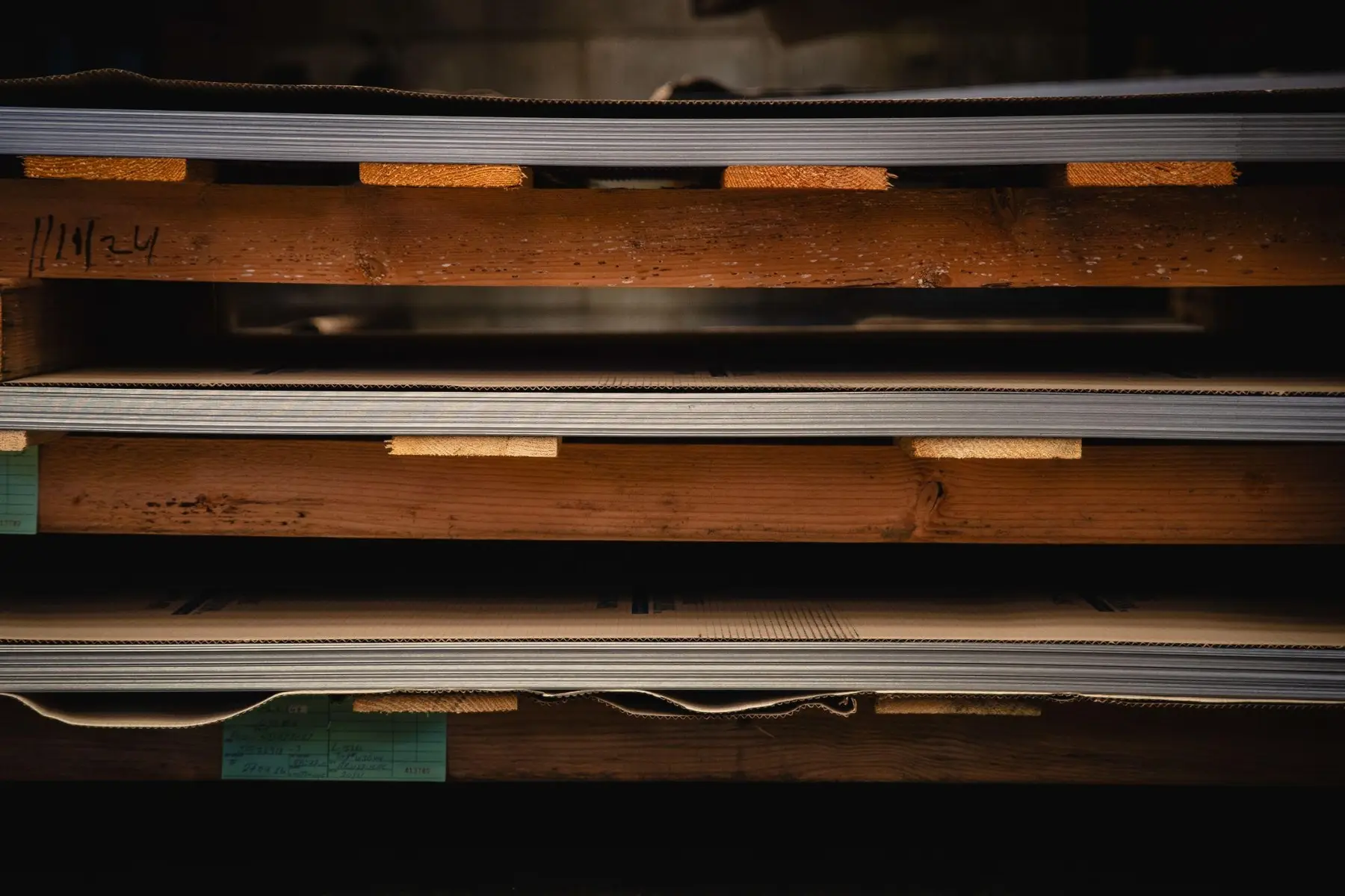 Leveled stainless steel sheets stacked on wooden skids in the Globe Stainless warehouse
