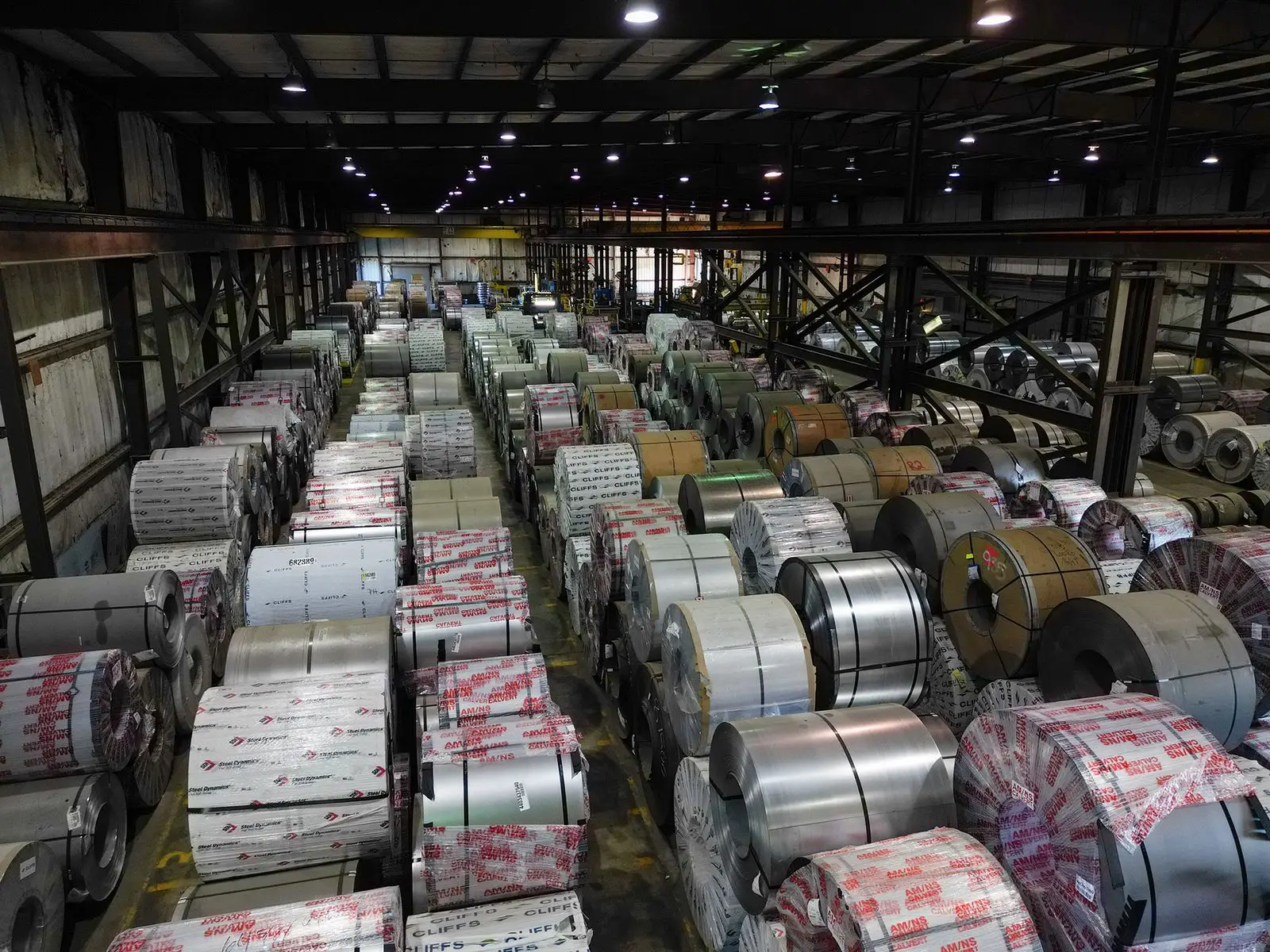 Overhead view of rows of wrapped steel coils stored in a Grand Steel warehouse