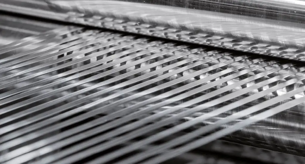 Narrow precision metal strands running through a slitter at Hamilton Precision Metals
