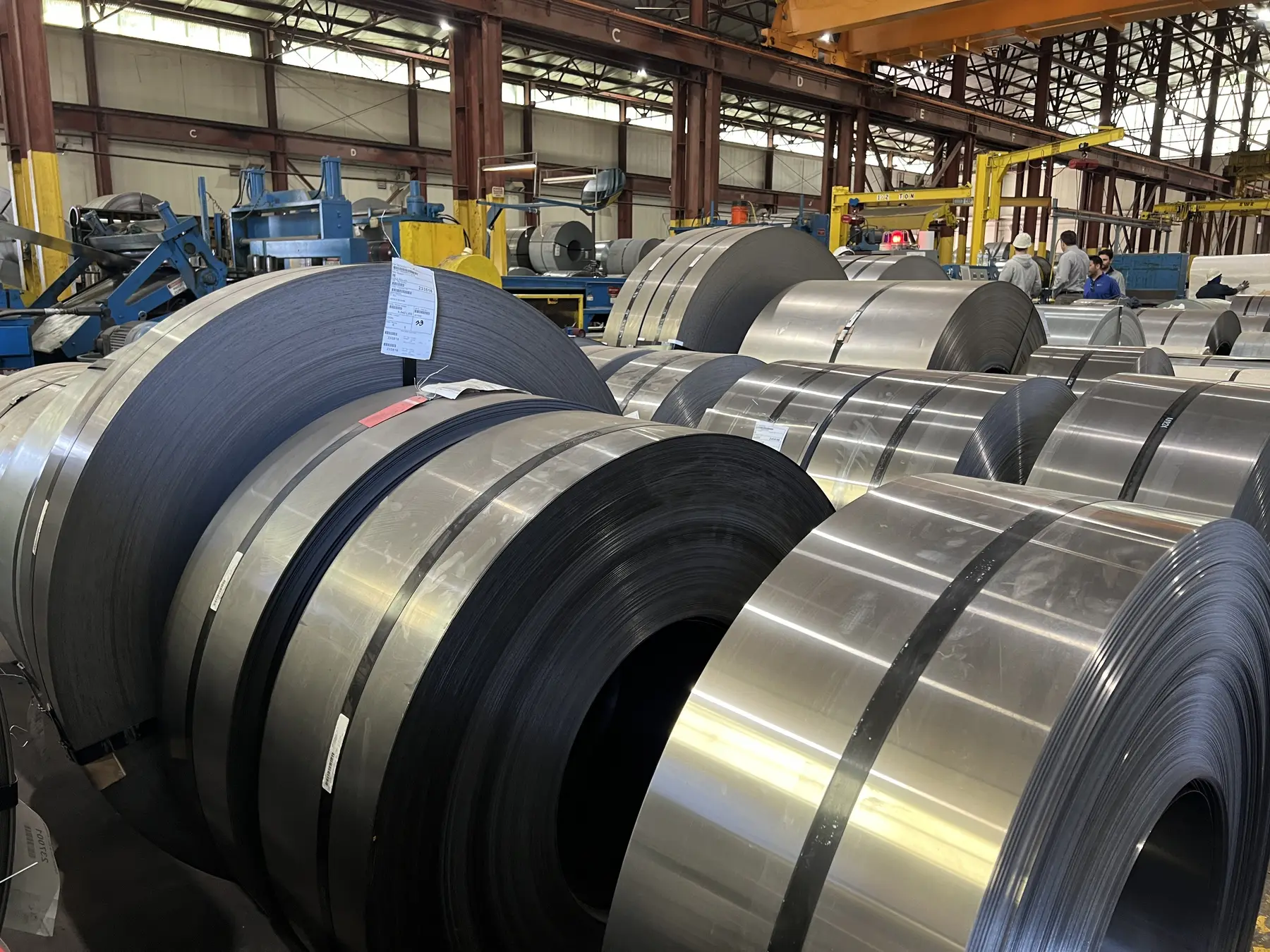 Rows of slit steel coils on the Harvard Steel plant floor in front of a slitting line