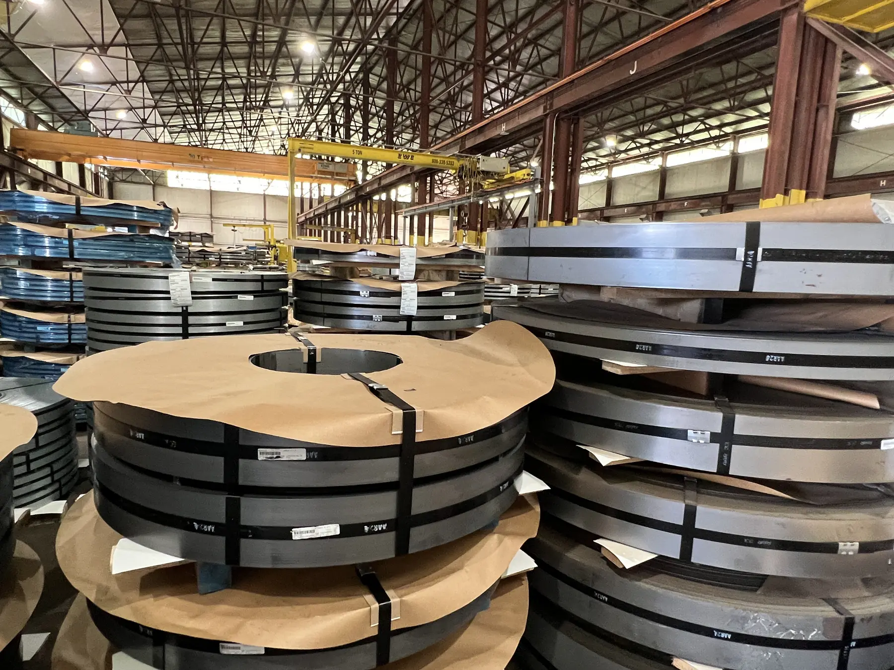 Banded slit coils stacked on paper-lined pallets under overhead cranes in the Harvard Steel warehouse