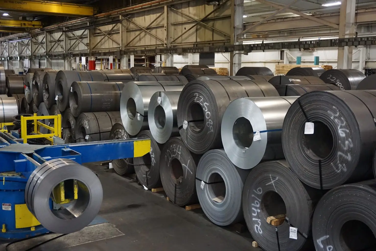 Rows of hot-rolled and cold-rolled steel coils on the floor of a Hascall Steel warehouse bay