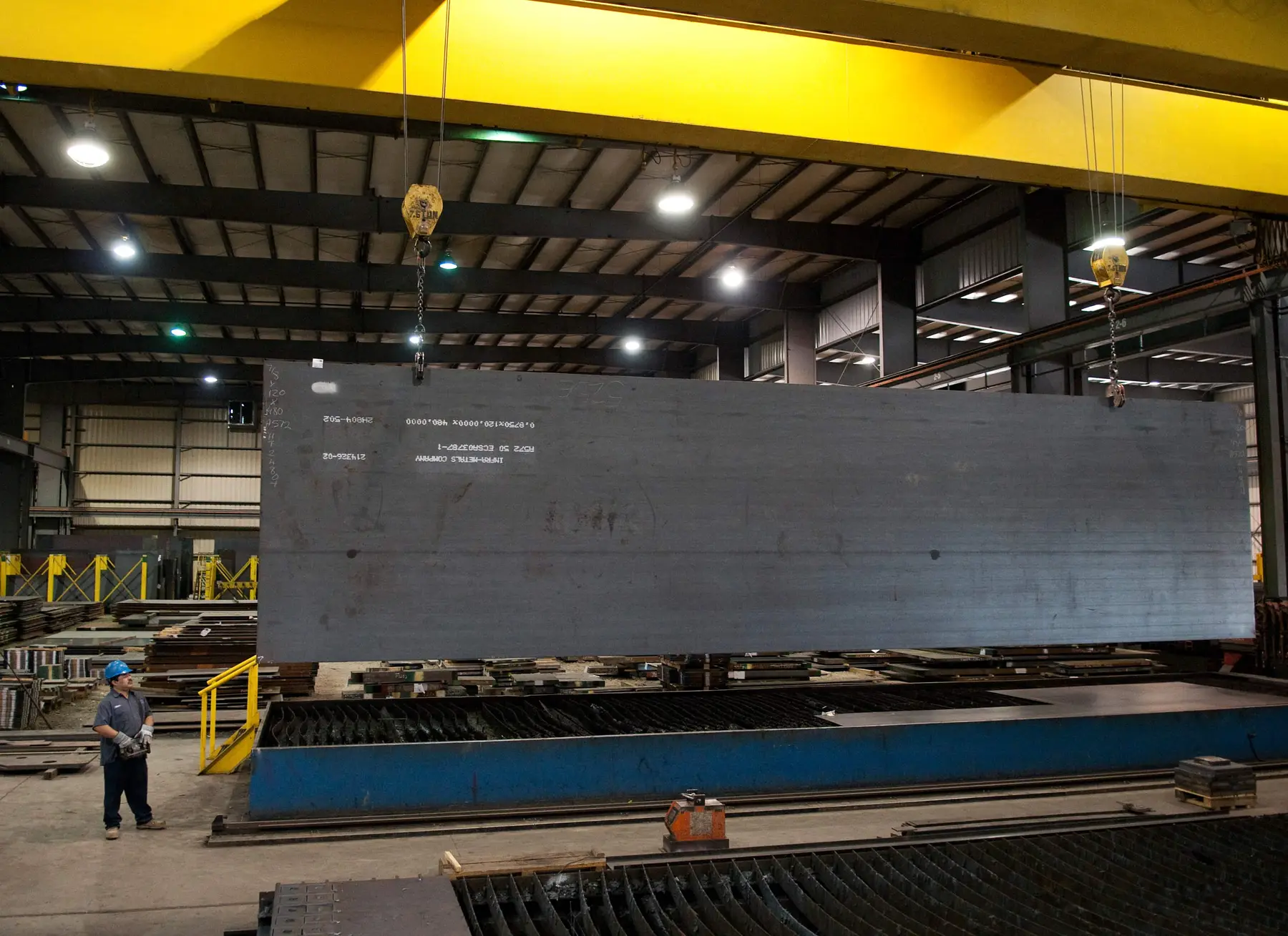 Large steel plate lifted by crane onto a plate burning table in the Infra-Metals burning department