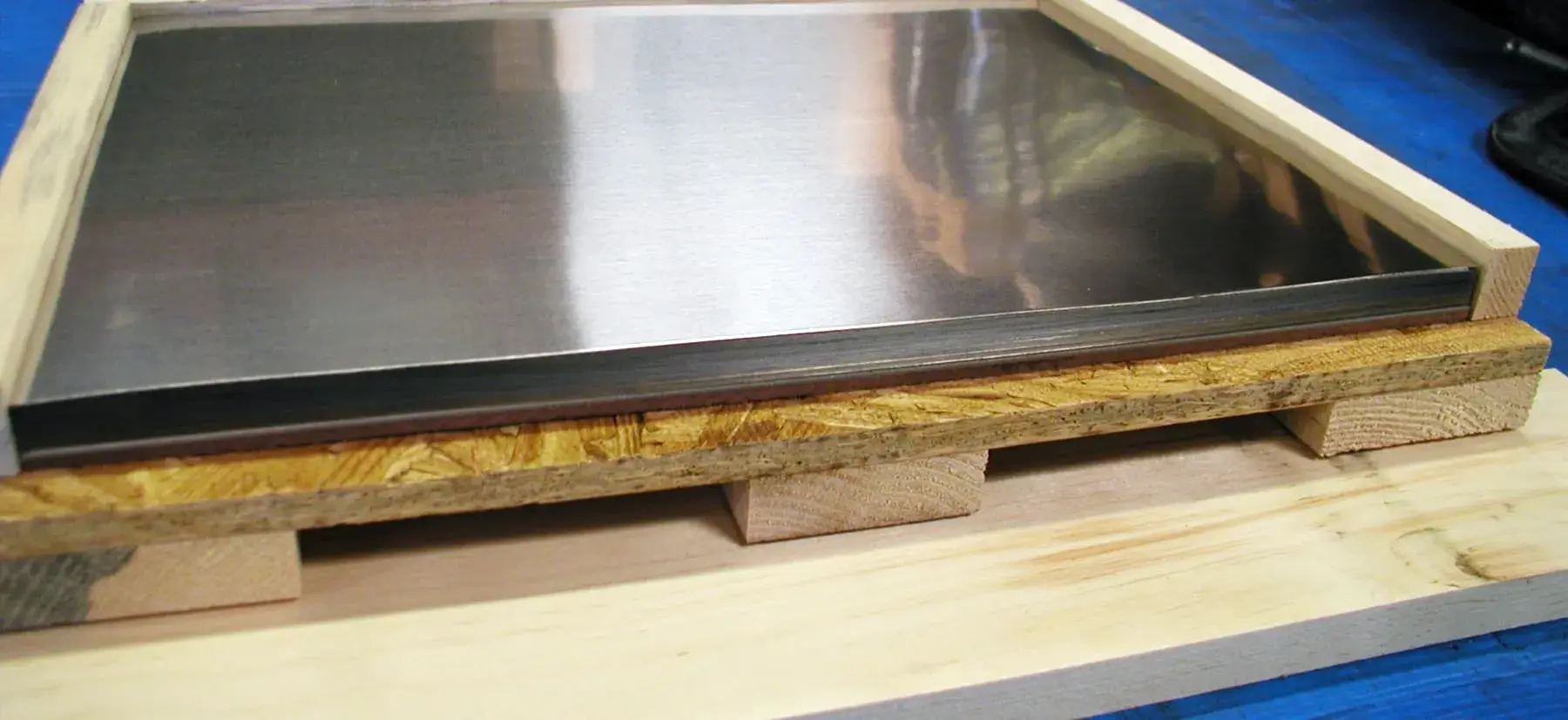 Stack of sheared and leveled stainless sheets packed on a wooden skid
