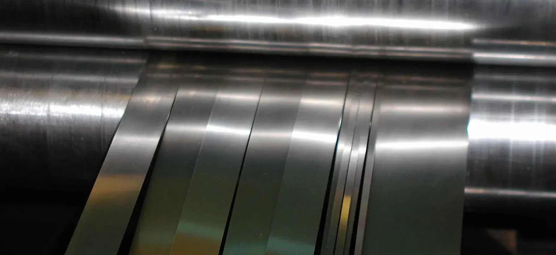 Close-up of bright stainless steel strip being slit into narrow widths at Integrity Metals & Slitting