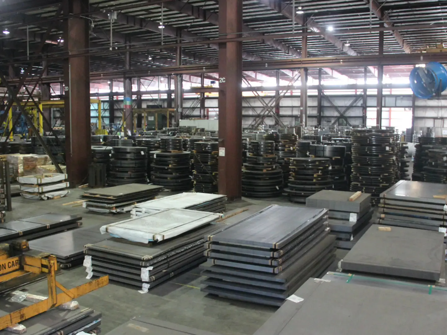 Bundles of cut steel sheets and blanks staged across JM Steel's processing floor