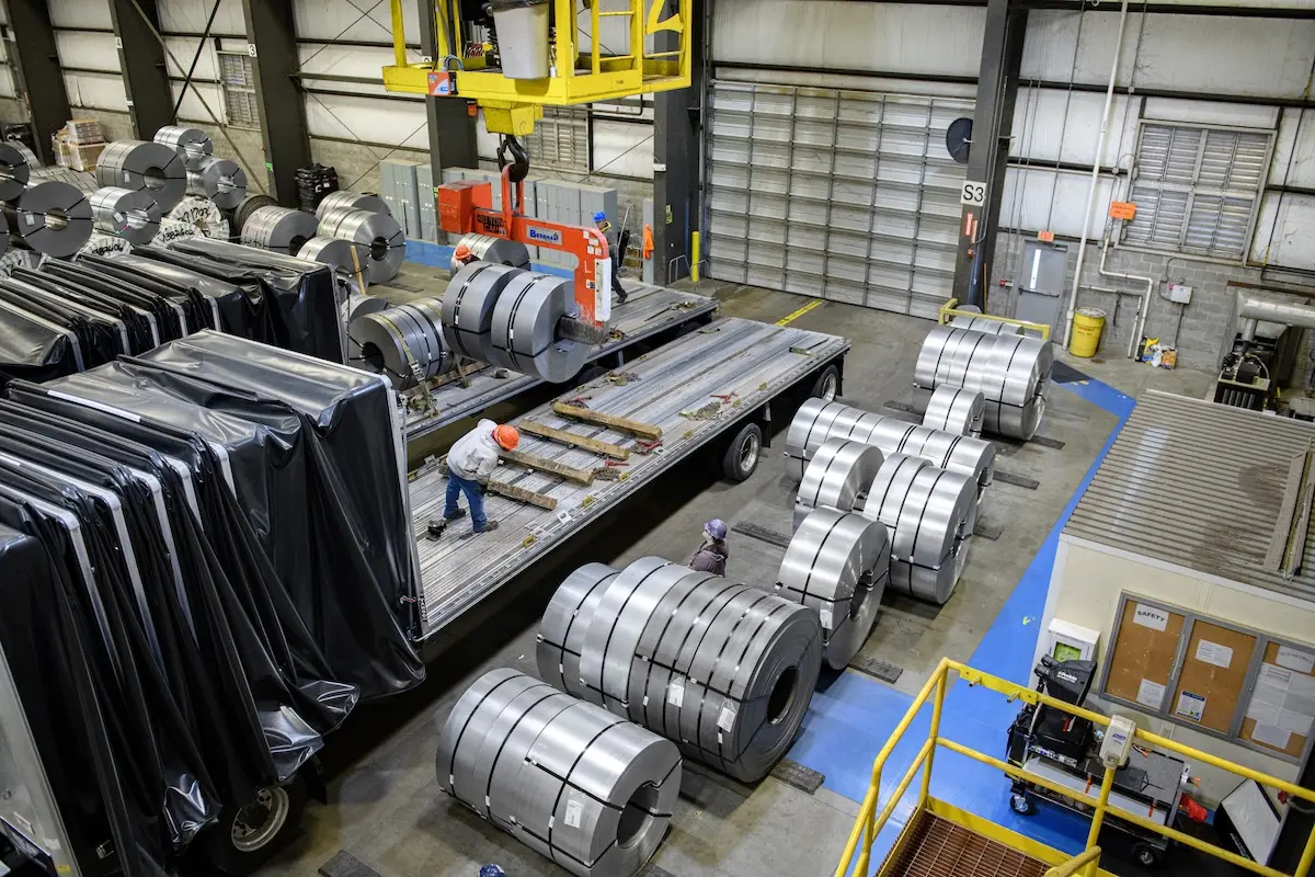 Slit steel coils staged beside a flatbed trailer for loading in Kenwal's warehouse