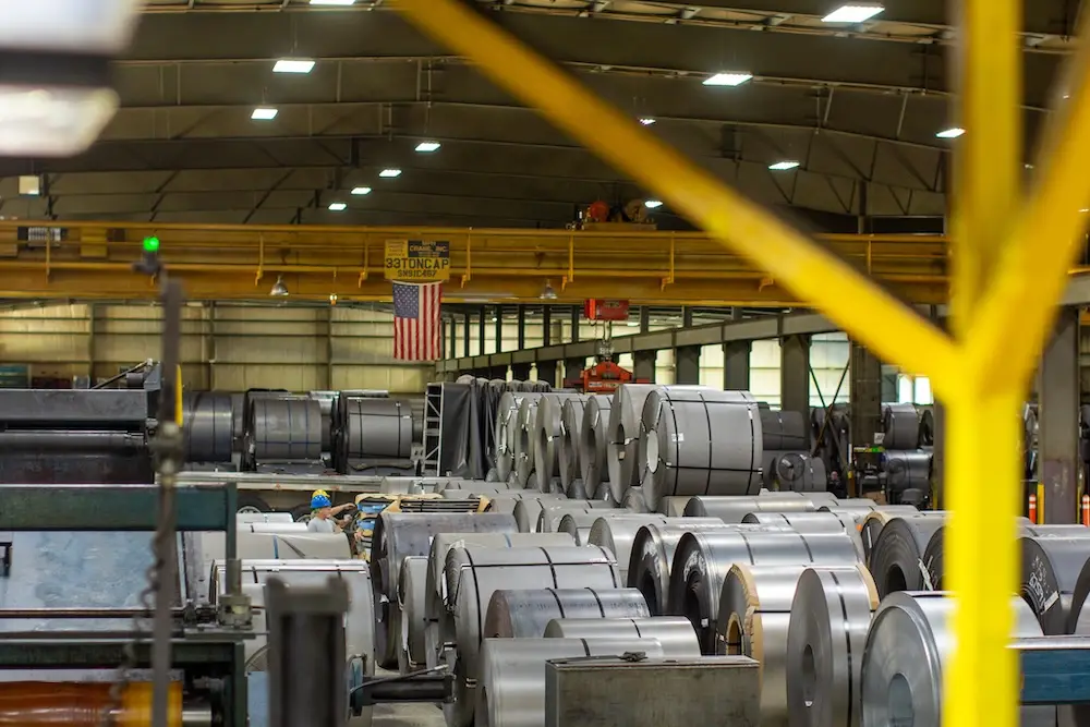Inside a Kenwal Steel service center bay with processed coils and overhead cranes