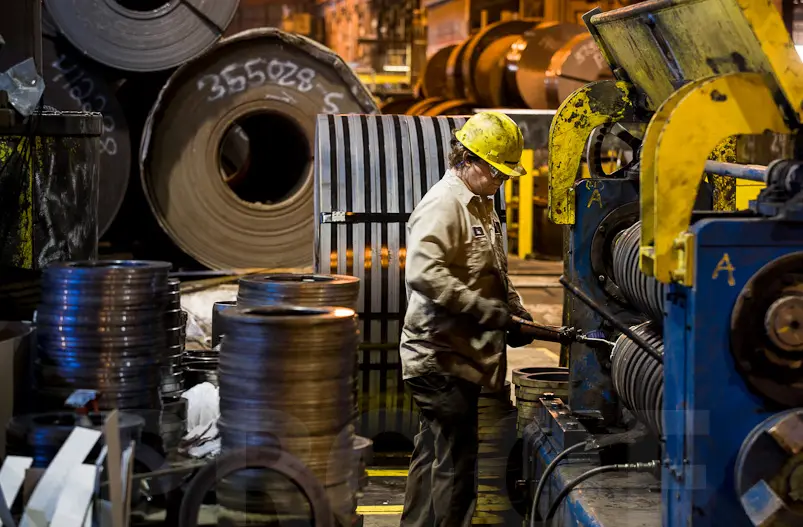 Operator at the recoiler of a Liberty Steel Processing slitting line with slit steel coils in the foreground