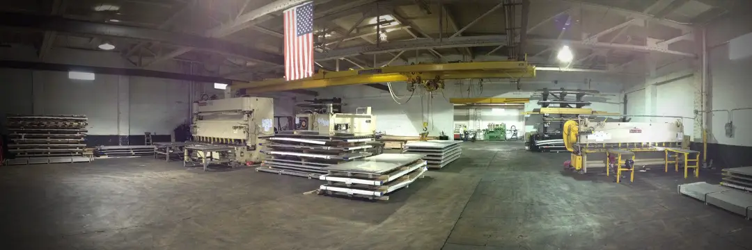 M&M Stainless Processing plant floor in Philadelphia with plate shears, an overhead crane and stacks of stainless plate
