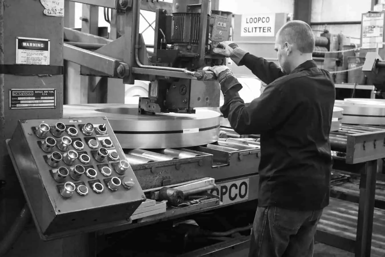 Operator at the controls of a Loopco slitter with slit coils on the exit table