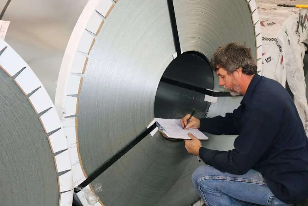 Employee recording details from a wrapped master coil in the warehouse