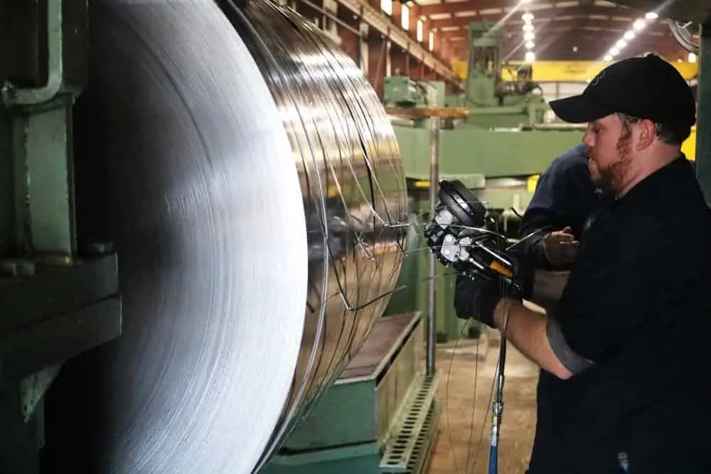 Operator working beside a steel coil mounted on a processing line