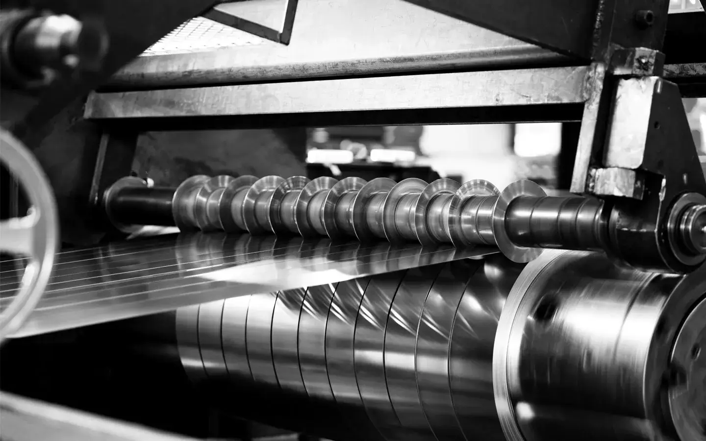 Slitter knives cutting steel strip on a Majestic Steel slitting line, black and white
