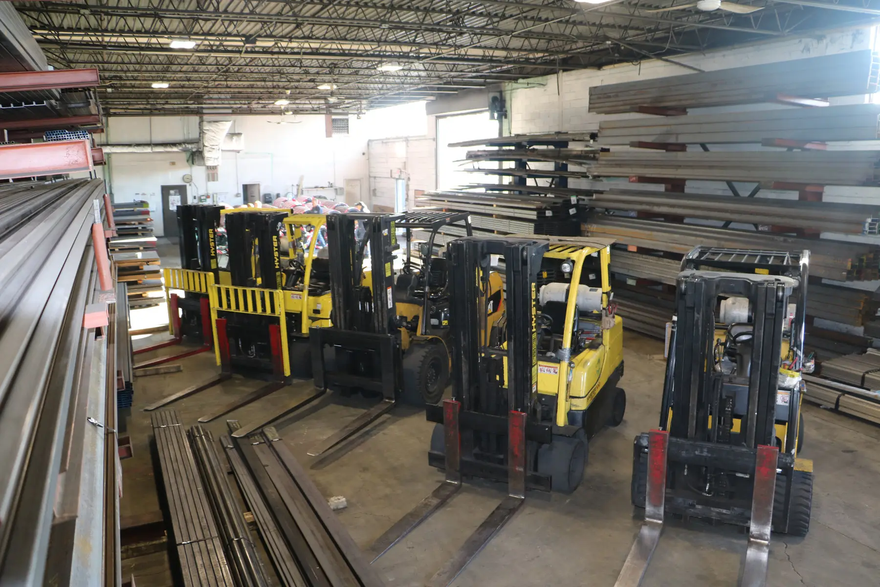 Forklifts parked beside long-product racks inside the Metal Masters warehouse in Ronkonkoma