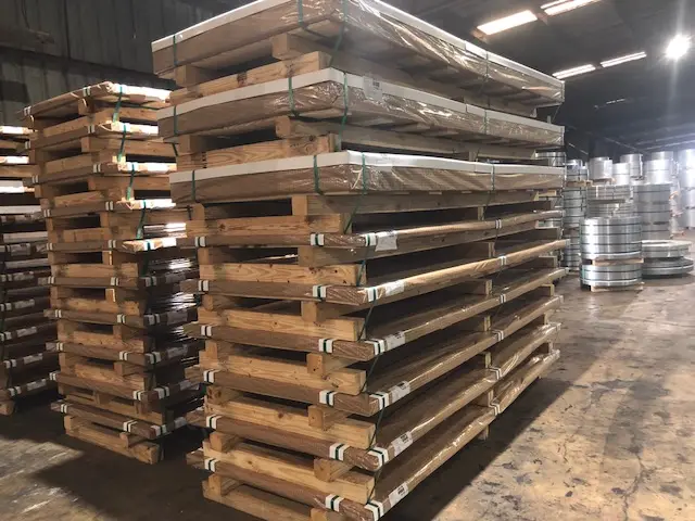 Banded packs of cut-to-length sheet stacked on wooden skids inside the Metal Processors warehouse