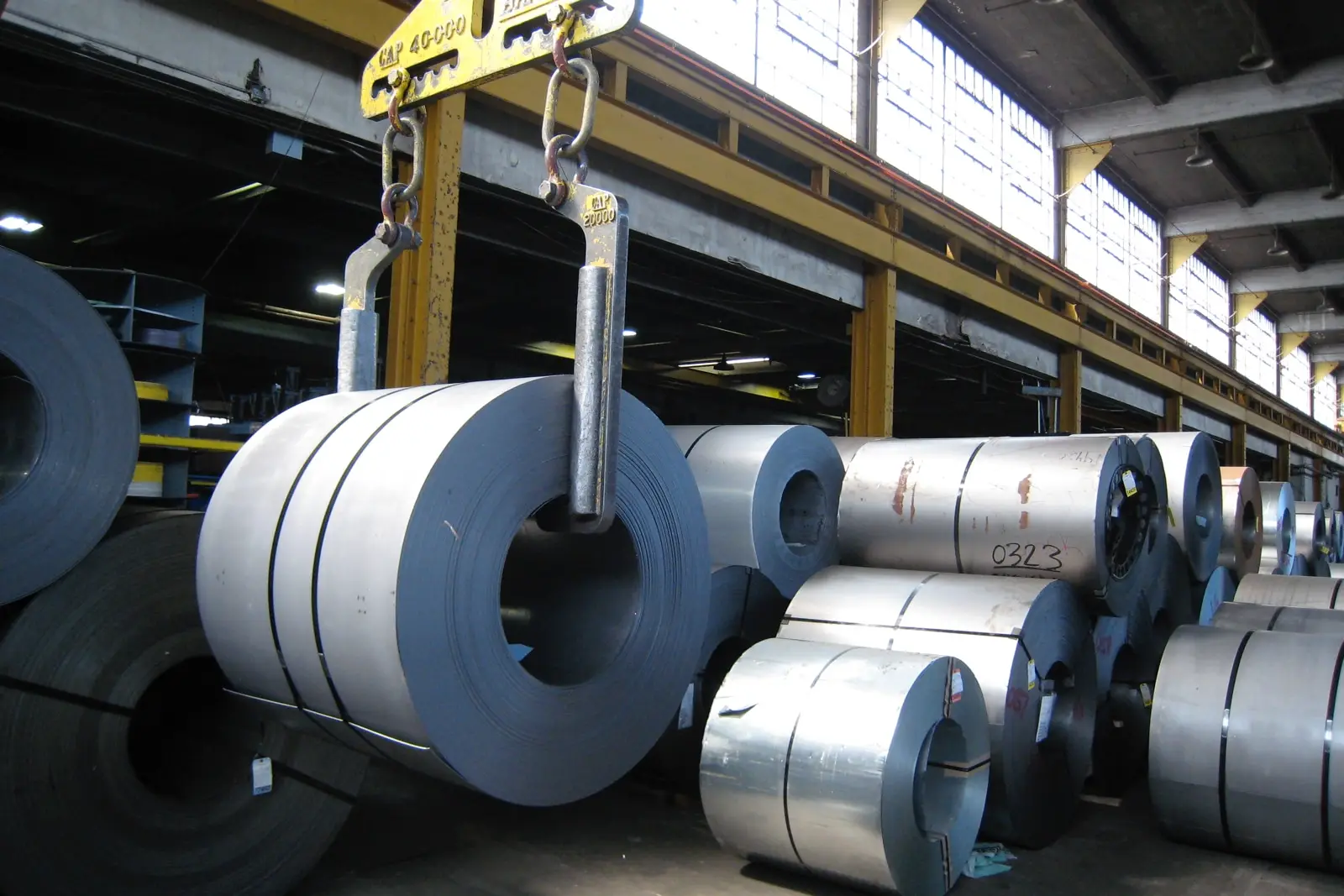 Overhead crane lifting a galvanized coil among rows of flat-rolled coils in Midland Steel's Bronx warehouse