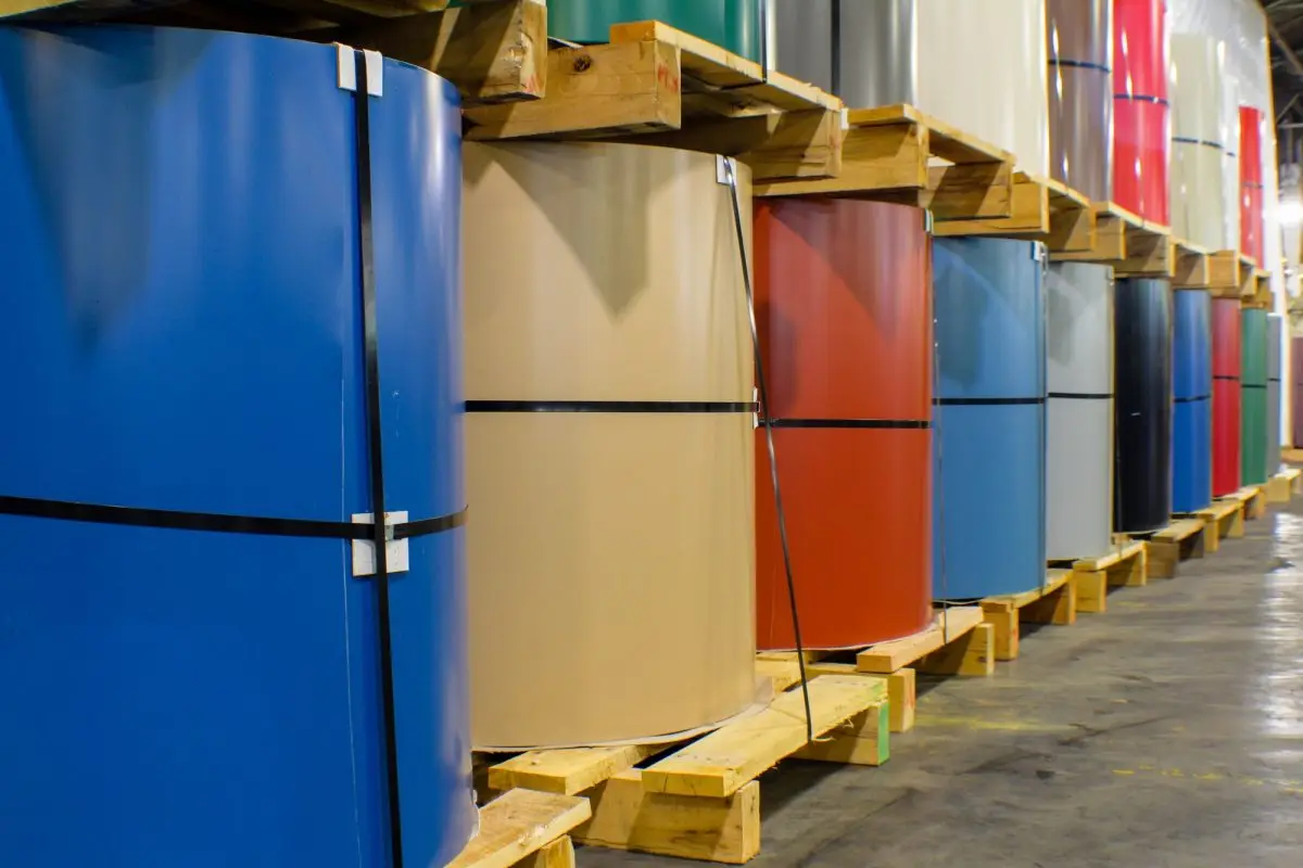 Pre-painted steel coils in blue, tan, red and white on pallets in warehouse