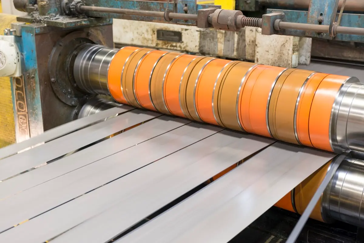 Galvanized steel strip passing through slitter knives with orange stripper rings