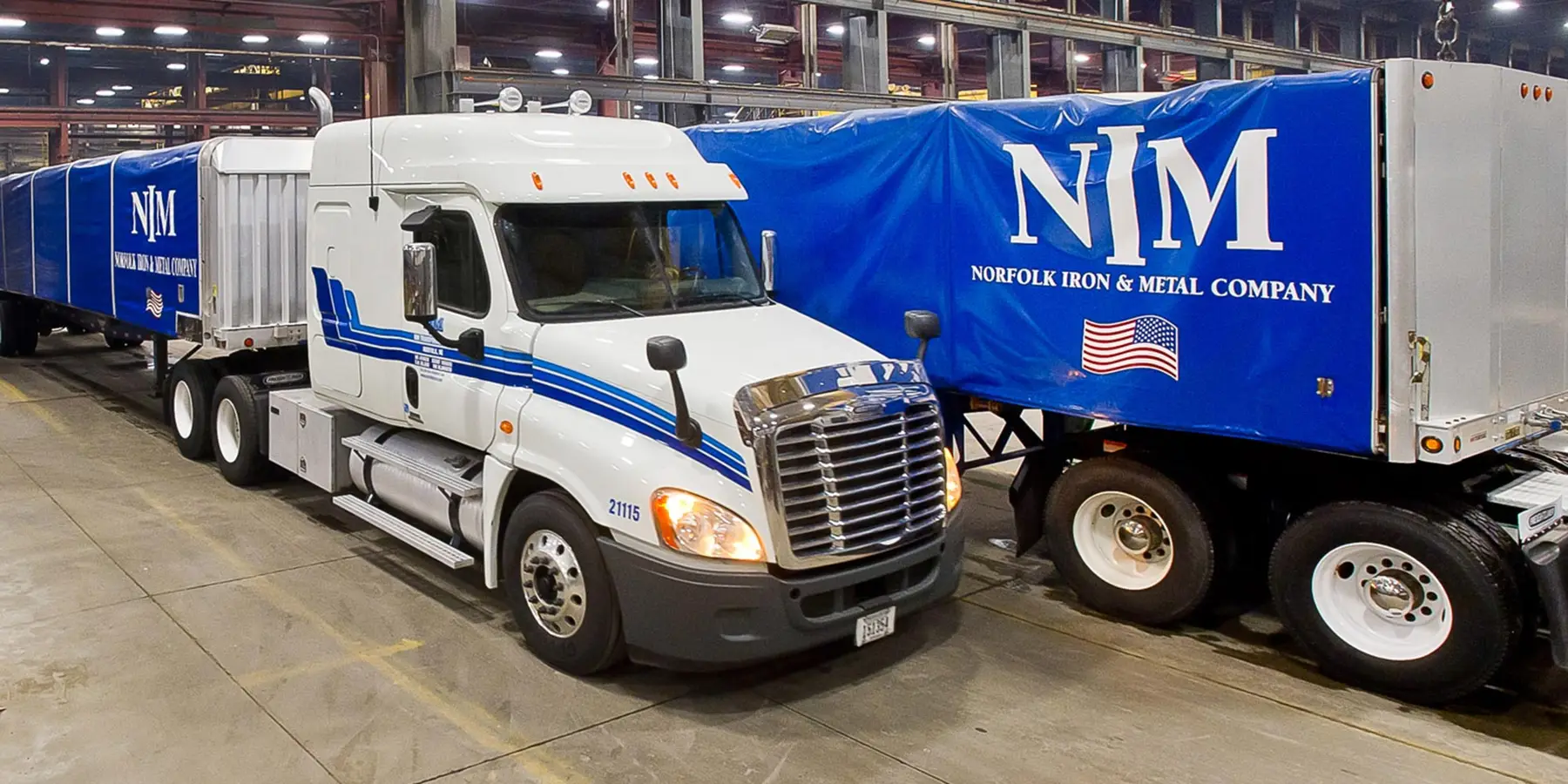 Norfolk Iron & Metal branded delivery trucks loading inside a steel warehouse