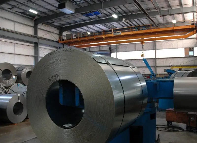 Steel master coil staged at a processing line inside the Oregon Metal Services plant under an overhead crane