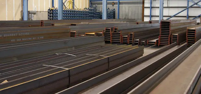 Stock-length wide-flange beams stored inside the Orkin Steel warehouse