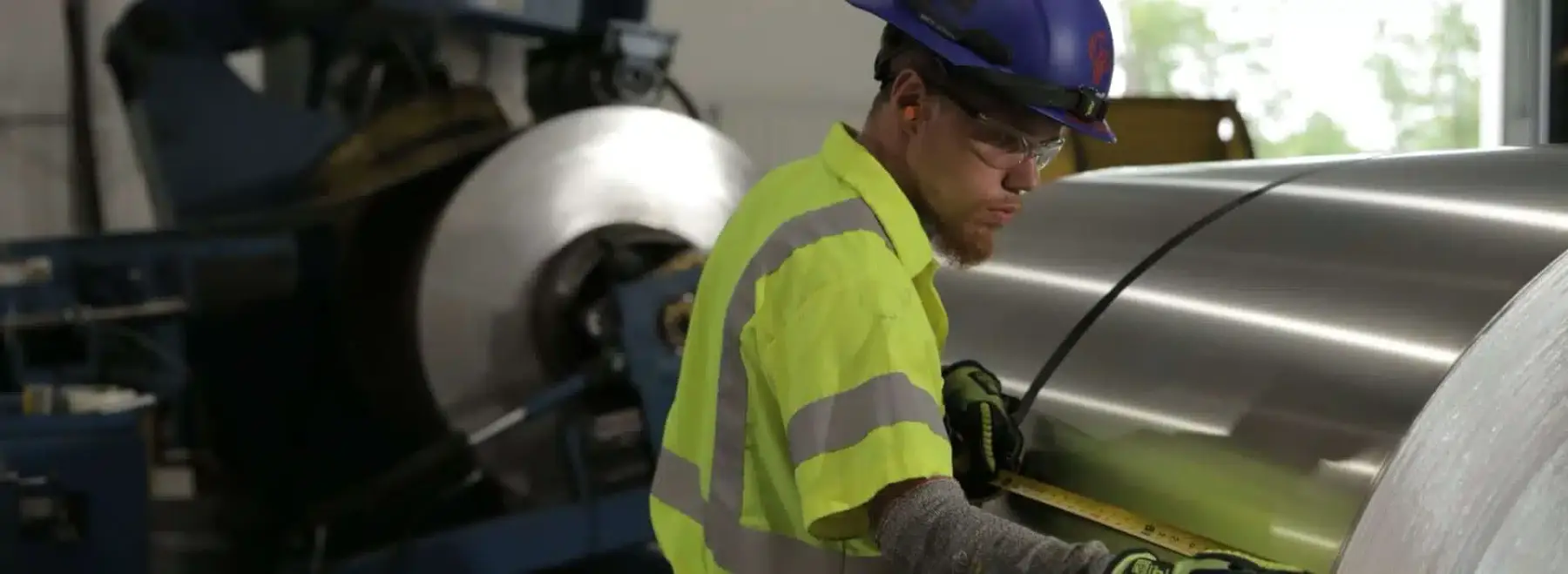 Operator inspecting a bright metal coil at a Phoenix Metals processing line