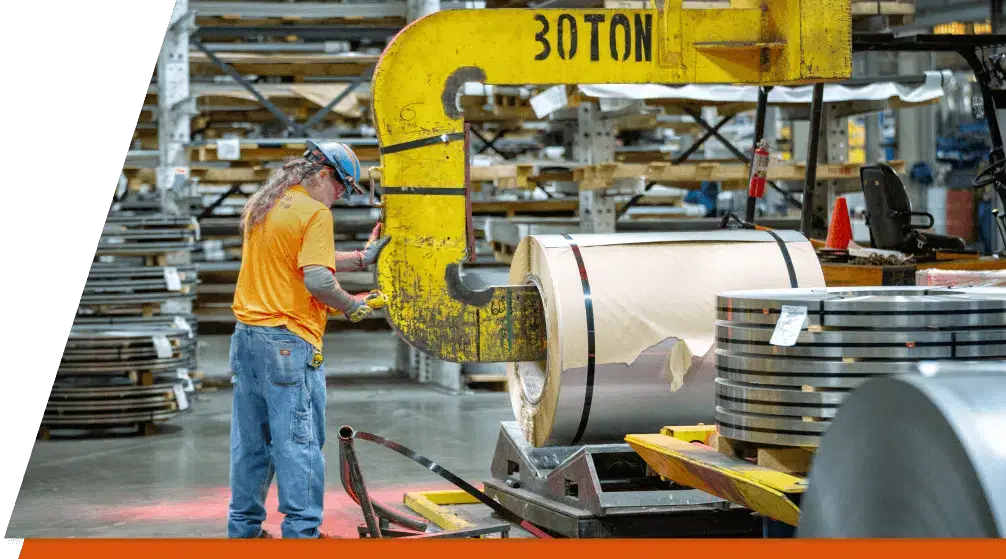 Coil lifter placing a steel coil beside racks of sheet inventory in a Phoenix Metals warehouse