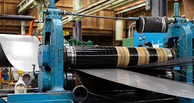 Steel strip feeding through a slitter head at Premium Metals