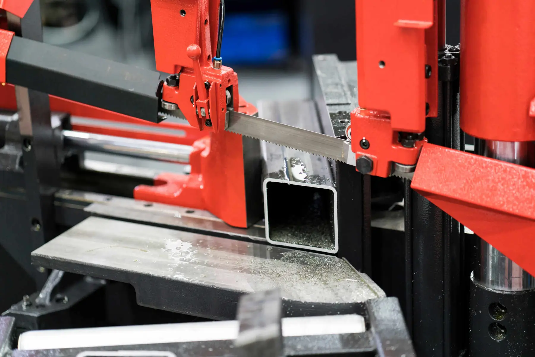 Band saw cutting rectangular steel tubing to length