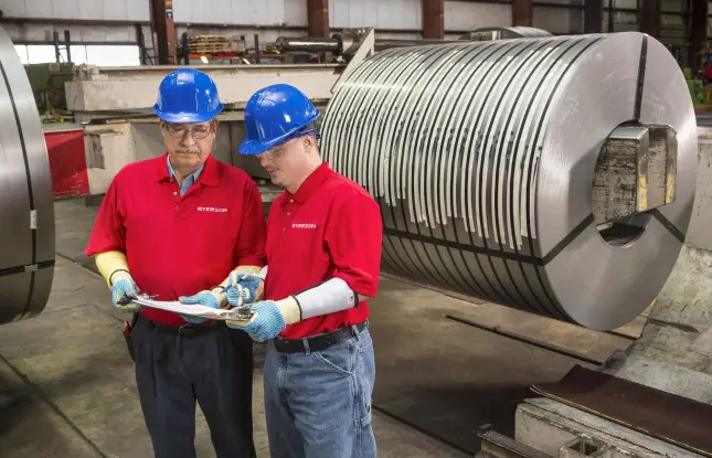 Ryerson team members reviewing paperwork beside a slit steel coil in a processing bay