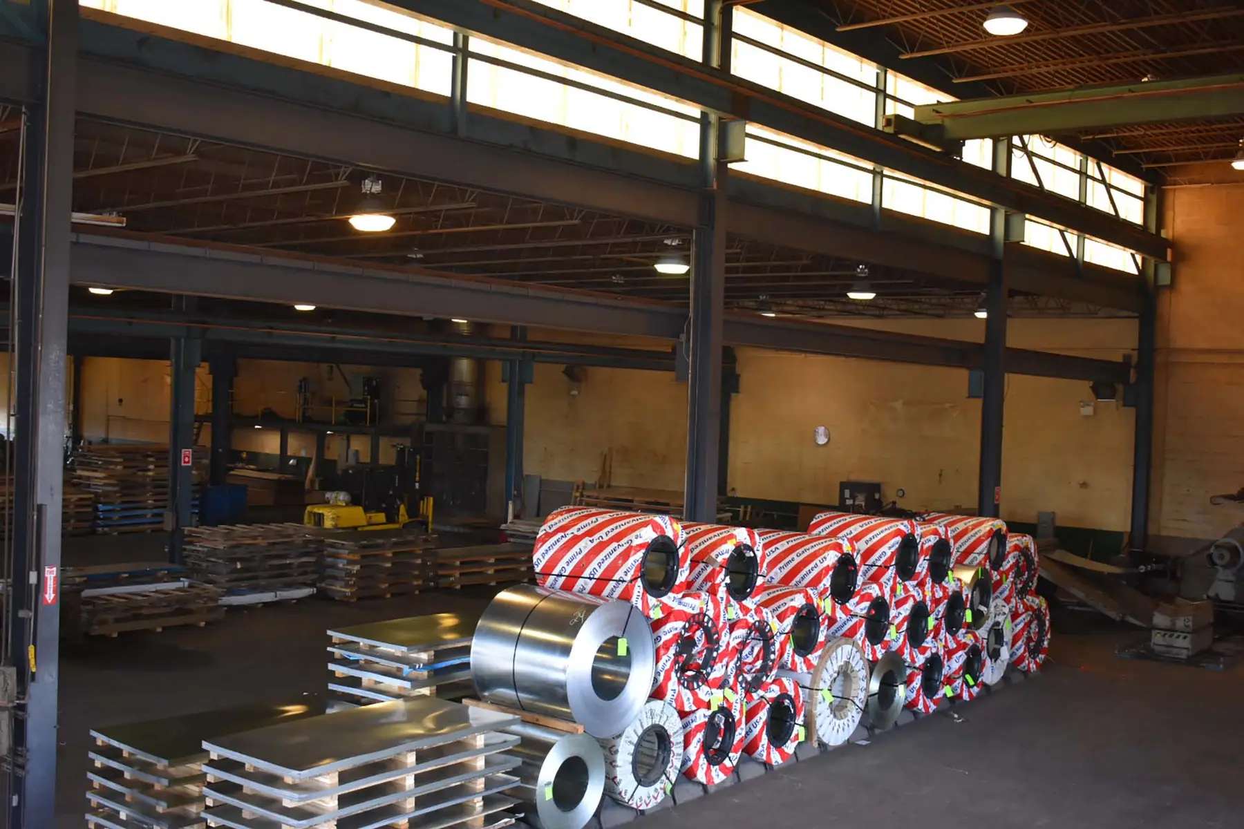 Wrapped galvanized coils and bundled sheet stock on the floor of Sherwood Steel's Bensalem warehouse